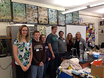 Faculty and students standing in a classroom lab