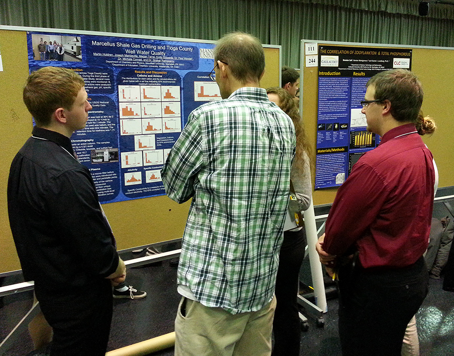 Students explaining their research poster to a viewer