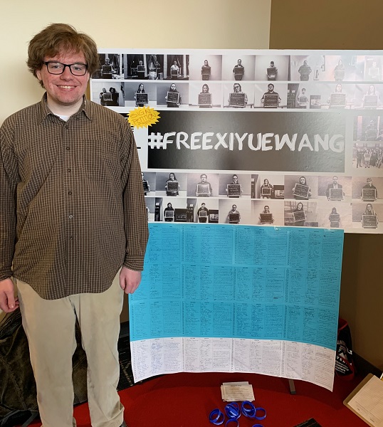 Student standing in front of poster that says #FreeXiyueWang
